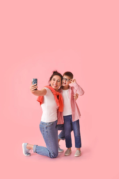 Νεαρή γυναίκα και ο γιος της βγάζουν selfie σε έγχρωμο φόντο - Φωτογραφία, εικόνα