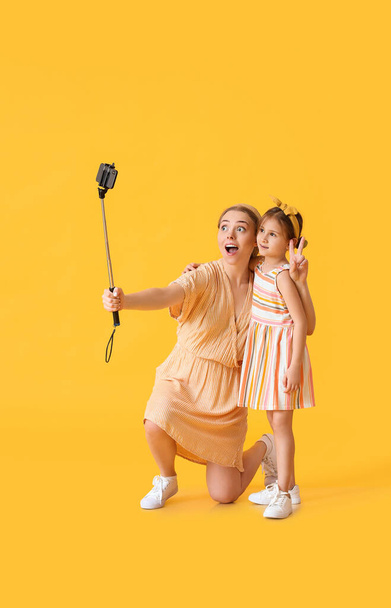 Junge Frau und ihre kleine Tochter machen Selfie auf farbigem Hintergrund - Foto, Bild