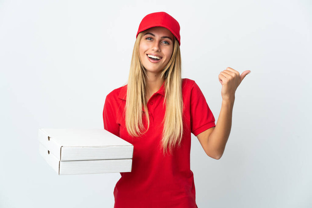 Kobieta dostarczająca pizzę trzymająca pizzę w izolacji na białym tle wskazując na bok, aby przedstawić produkt - Zdjęcie, obraz