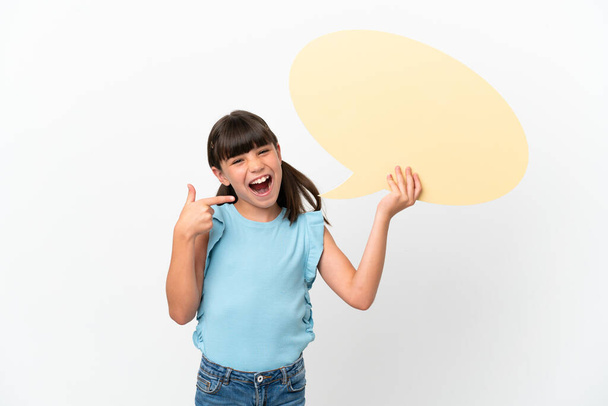 Little caucasian kid isolated on white background holding an empty speech bubble and pointing it - Foto, Imagen