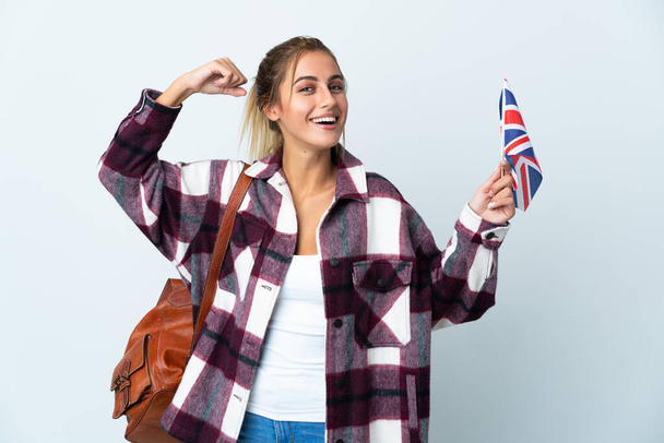 白い背景に英国国旗を掲げた若い女性が強いジェスチャーを行う - 写真・画像