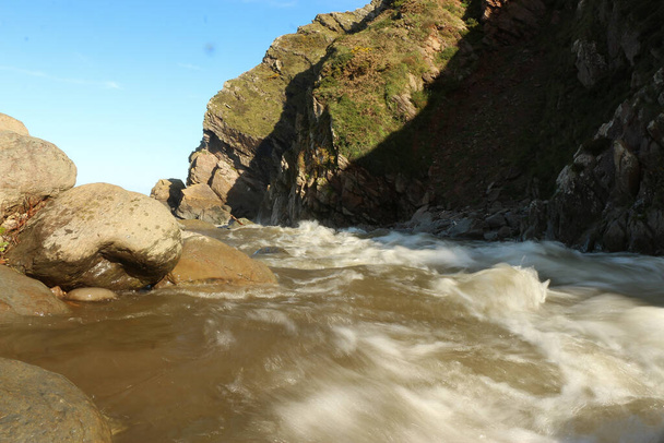 The Heddon river swollen by heavy rainfall and floodwater crashing through Heddon valley on the way out to sea on the coast of North Devon in the south west of England - Photo, Image
