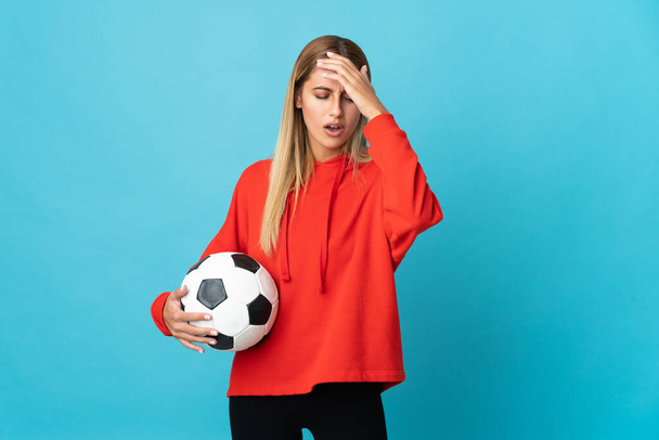 Genç futbolcu kadın mavi arka planda izole edilmiş, baş ağrısı var. - Fotoğraf, Görsel