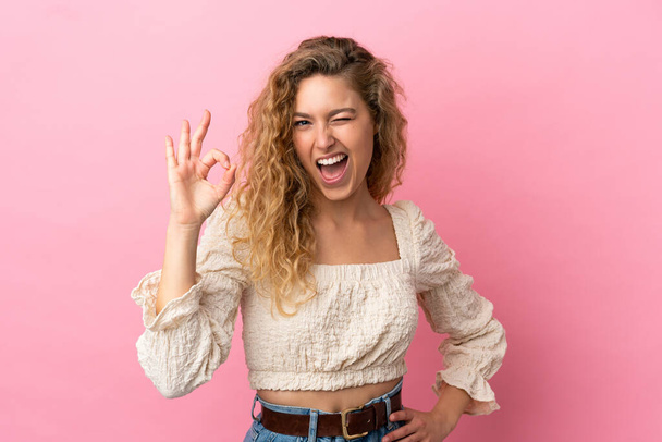 Young blonde woman isolated on pink background showing ok sign with fingers - 写真・画像
