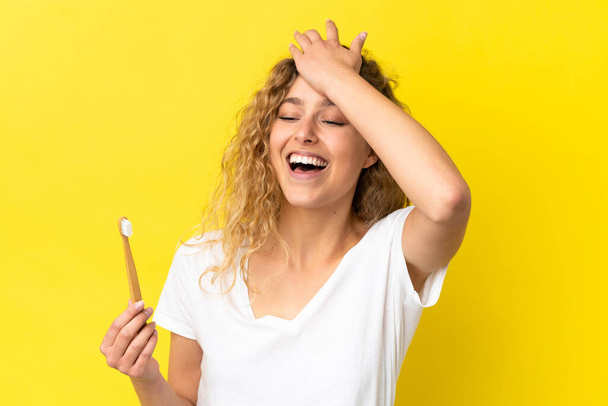 Young caucasian woman holding a brushing teeth isolated on yellow background has realized something and intending the solution - Photo, Image