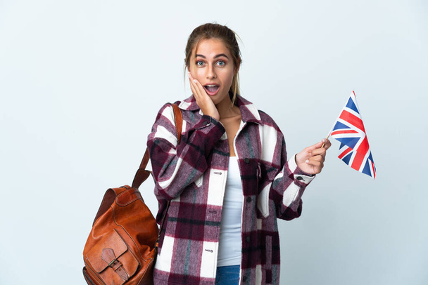 Junge Frau mit britischer Flagge auf weißem Hintergrund und schockiertem Gesichtsausdruck - Foto, Bild