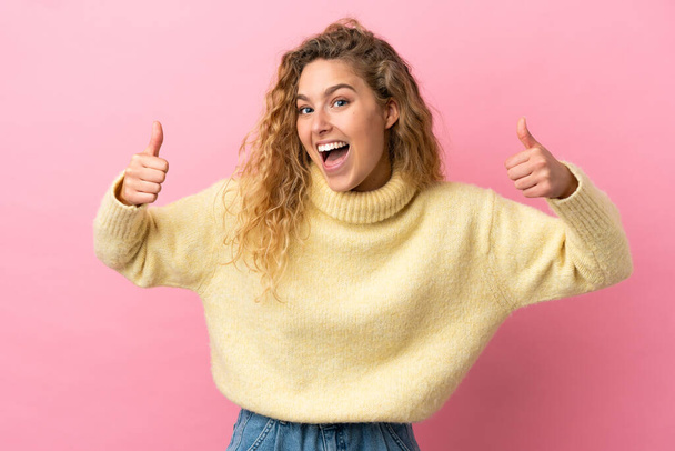 Young blonde woman isolated on pink background giving a thumbs up gesture - Foto, Imagen