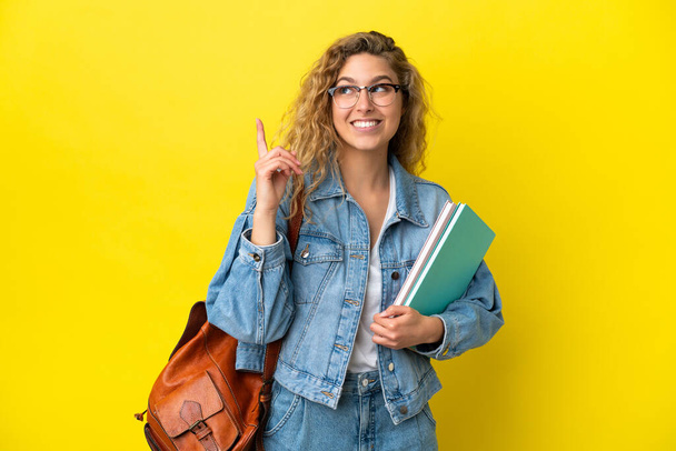 Young student caucasian woman isolated on yellow background pointing up a great idea - Photo, Image
