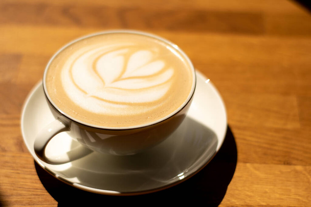 Mug of cappuccino on a wooden table - Фото, зображення