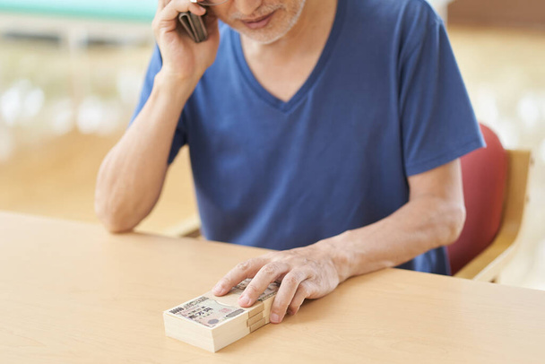 Personas mayores que preparan dinero en efectivo en llamadas telefónicas fraudulentas - Foto, Imagen