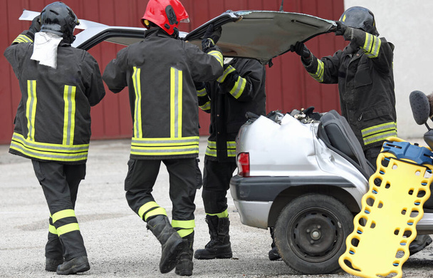 praca zespołowa strażaków w akcji podczas ratowania rannych po wypadku samochodowym z noszami - Zdjęcie, obraz