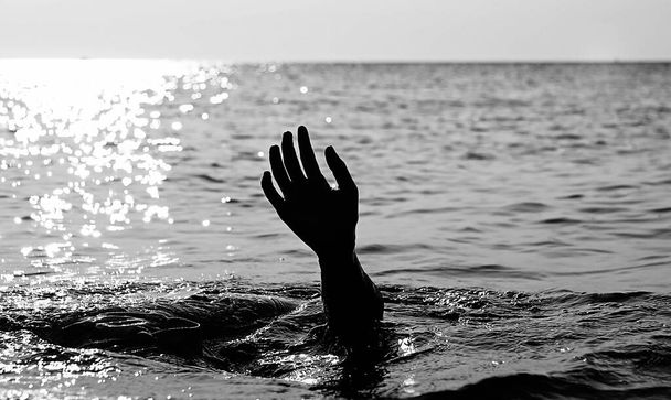 hand of the drowning person in the middle of the ocean in black and white to make the effect more dramatic - Photo, Image