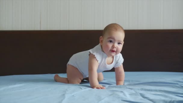 幸せな赤ん坊はベッドの上を這う。乳児の赤ちゃんは家の中で家族と遊ぶとキャッチアップゲーム中に迅速にクロールする方法を学びます. - 映像、動画