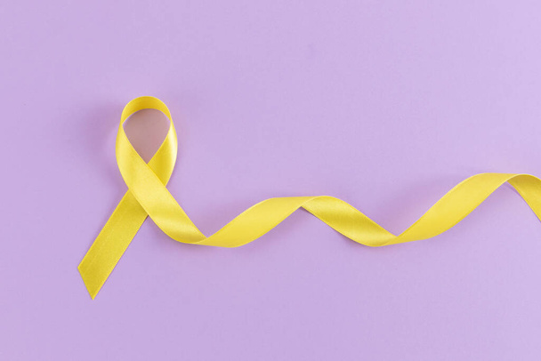 Yellow ribbon on purple background - Valokuva, kuva