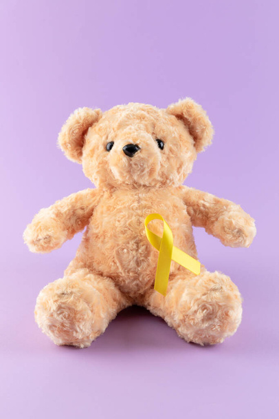 teddy bear and yellow ribbon, purple background - Фото, зображення