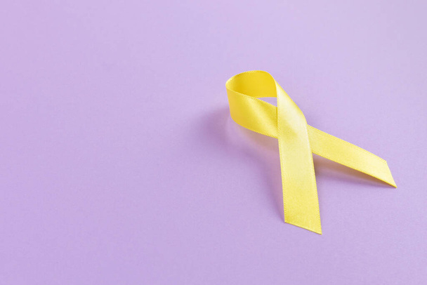 Yellow ribbon on purple background - Foto, Imagen
