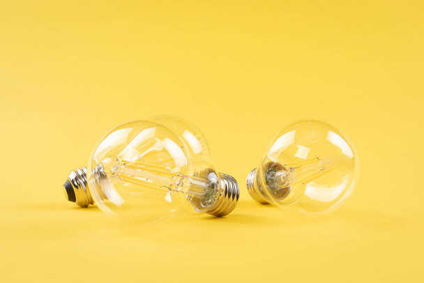 Transparent bulbs on yellow background - Foto, Imagen