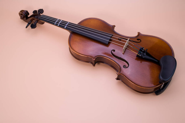 A high angle shot of violin isolated on light pink background - Zdjęcie, obraz