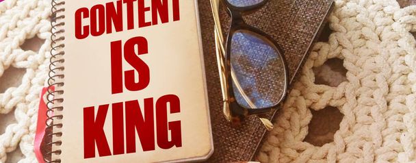 Обложка блокнота со словами Content Is King, очки и ручка. Концепция копирайтинга и образования. - Фото, изображение