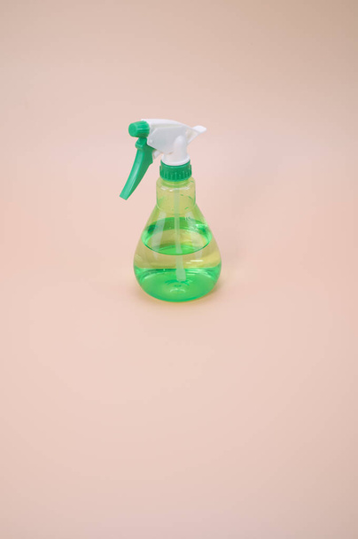 A vertical shot of green plastic sprayer isolated on light pink background - Foto, imagen