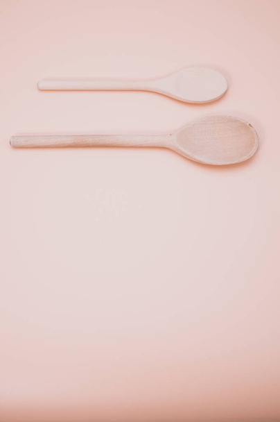A vertical of wooden spoons isolated on light pink background with copy space - Фото, зображення