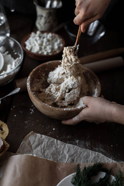 A vertical shot of female hands mixing dough in a wooden bowl - Zdjęcie, obraz