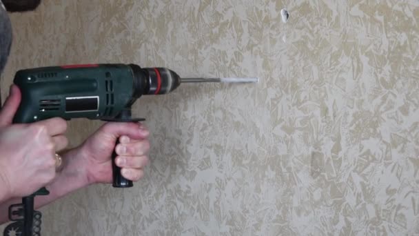 Las manos masculinas hacen agujero usando taladro eléctrico con broca de torsión - Metraje, vídeo