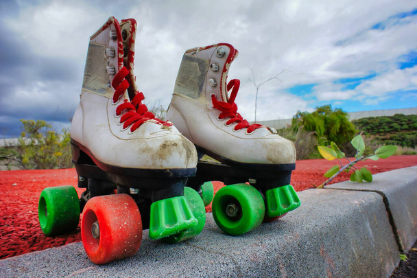 A shot of the roller skates with red and green wheels on the asphalt surface. - Photo, image