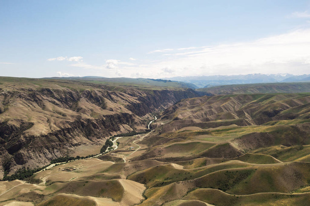 Vuorenhuiput ja niityt ovat valkoisten pilvien alla. Ammuttu Xinjiangissa, Kiinassa. - Valokuva, kuva