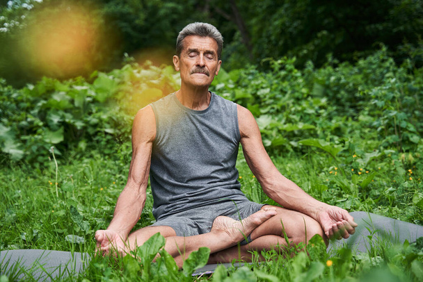 Senior man meditating in nature around the trees - Fotó, kép