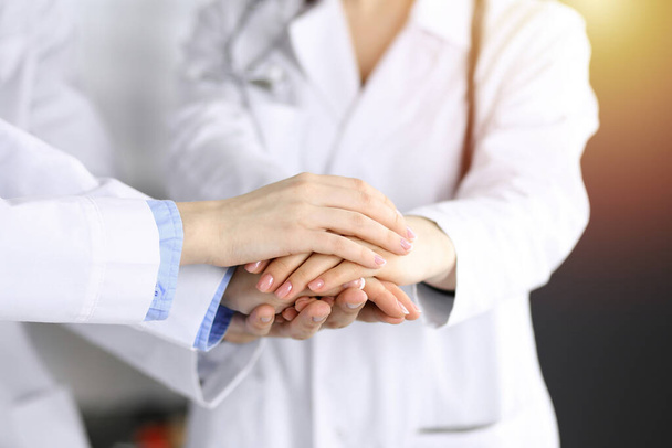 Groupe de médecins modernes joignant les mains comme un cercle. Travail d'équipe en médecine pendant la pandémie de coronavirus, covide 2019 - Photo, image