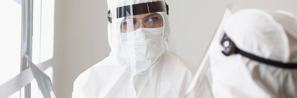 Koruyucu giysili ve gözlüklü iki doktor hastanın röntgenini çekiyorlar. - Fotoğraf, Görsel