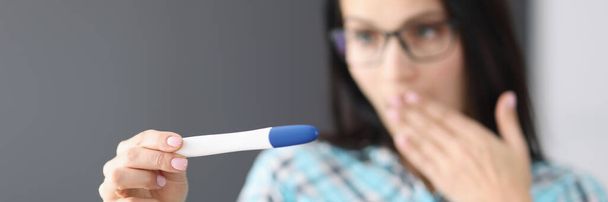 Zaskoczona kobieta trzymająca test ciążowy w ręce - Zdjęcie, obraz