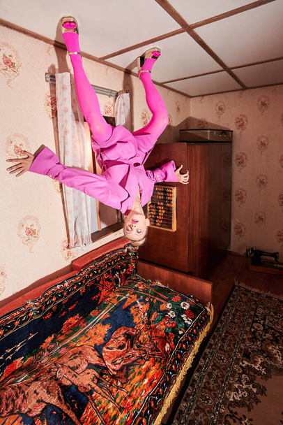 Woman wearing pink clothes standing at the ceiling at the interesting pose - Фото, изображение
