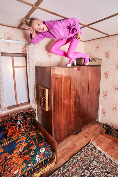 Woman in pink clothes standing at the ceiling at the wardrobe while posing - Valokuva, kuva