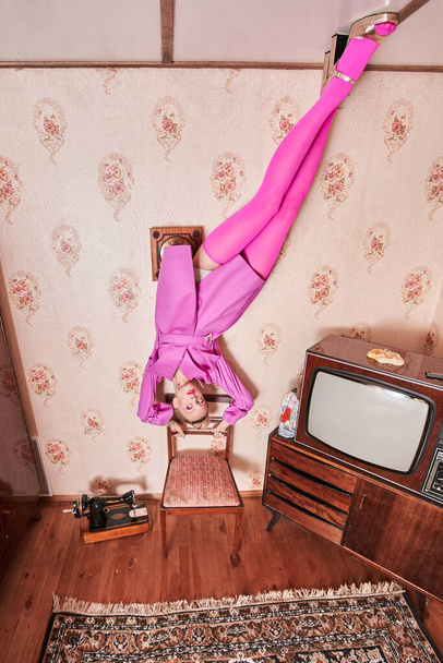 Woman wearing pink clothes looking away while standing at the ceiling - Foto, Bild