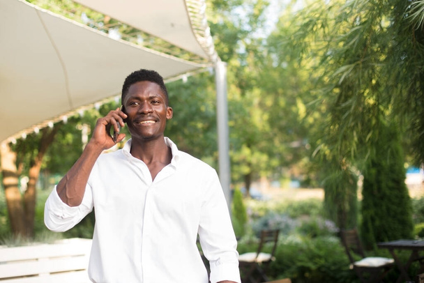 Χαρούμενος Αφροαμερικάνος με τηλέφωνο στο δρόμο.. - Φωτογραφία, εικόνα