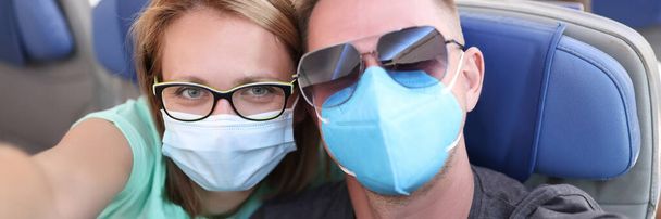 Man and woman wearing medical protective masks on plane - Foto, imagen