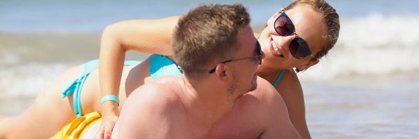 Un homme et une femme souriants reposent sur la plage - Photo, image