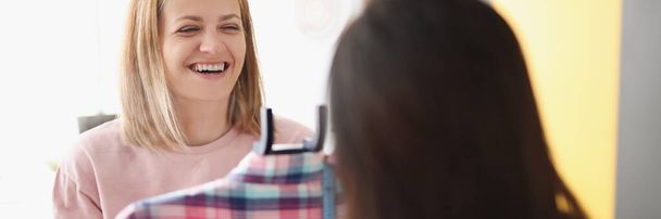 Smiling woman demonstrates clothes on hanger to client - Foto, Imagen