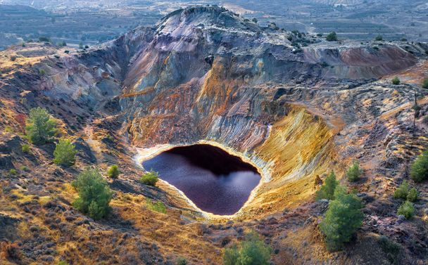 Acid red lake and colorful rocks in abandoned mine pit near Kampia, Cyprus. This area has large amounts of copper ore and sulfide deposits - Photo, Image