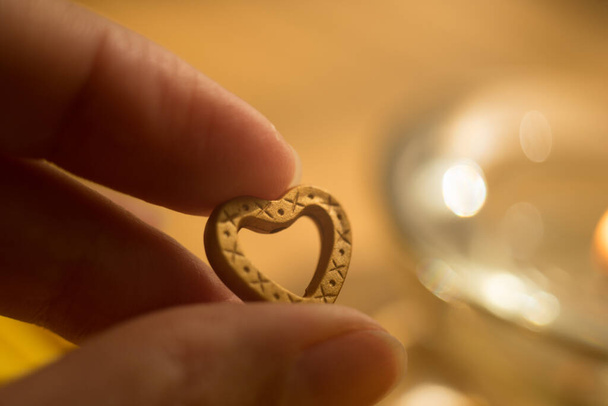 μεταλλική καρδιά σε γυναικεία δάχτυλα με χρυσό φως. - Φωτογραφία, εικόνα