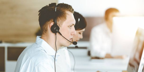 Businessman working at customer service office. Group of diverse operators at work in sunny call center - Фото, зображення