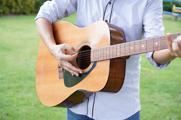 Guitarrista masculino tocando la guitarra acústica en la naturaleza del jardín como relajante y recreación para la terapia musical. Hombre feliz con instrumento de cuerda. - Foto, imagen
