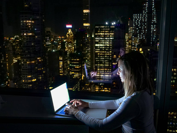 CERRAR: Joven empresaria trabajando en su portátil en Nueva York a altas horas de la noche. - Foto, Imagen