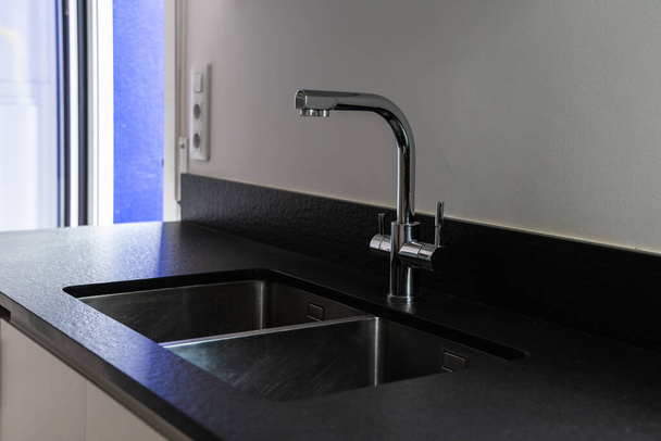 Un lavello in acciaio inox a doppia vasca in stile moderno, rubinetto in acciaio cromato in cucina - Foto, immagini