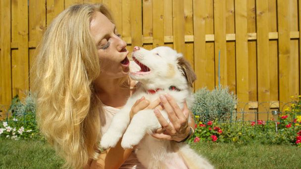 Šťastná dívka a bílé štěně se na sebe dívají s otevřenými ústy. - Fotografie, Obrázek