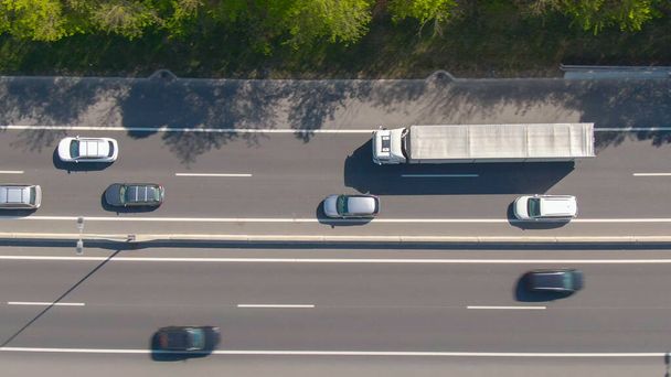 ARRIBA: Un camión blanco grande conduce a lo largo de la autopista durante un atasco de tráfico ligero. - Foto, imagen