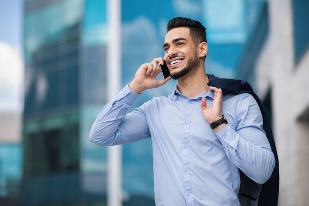 Happy muslim entrepreneur going home from job, talking on cellphone - Фото, зображення