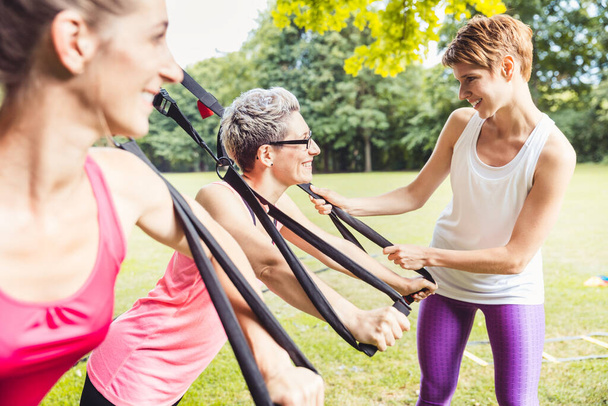 Glückliche reife athletische Frau macht Übungen mit der Personal Fitness Trainerin im Park - Foto, Bild